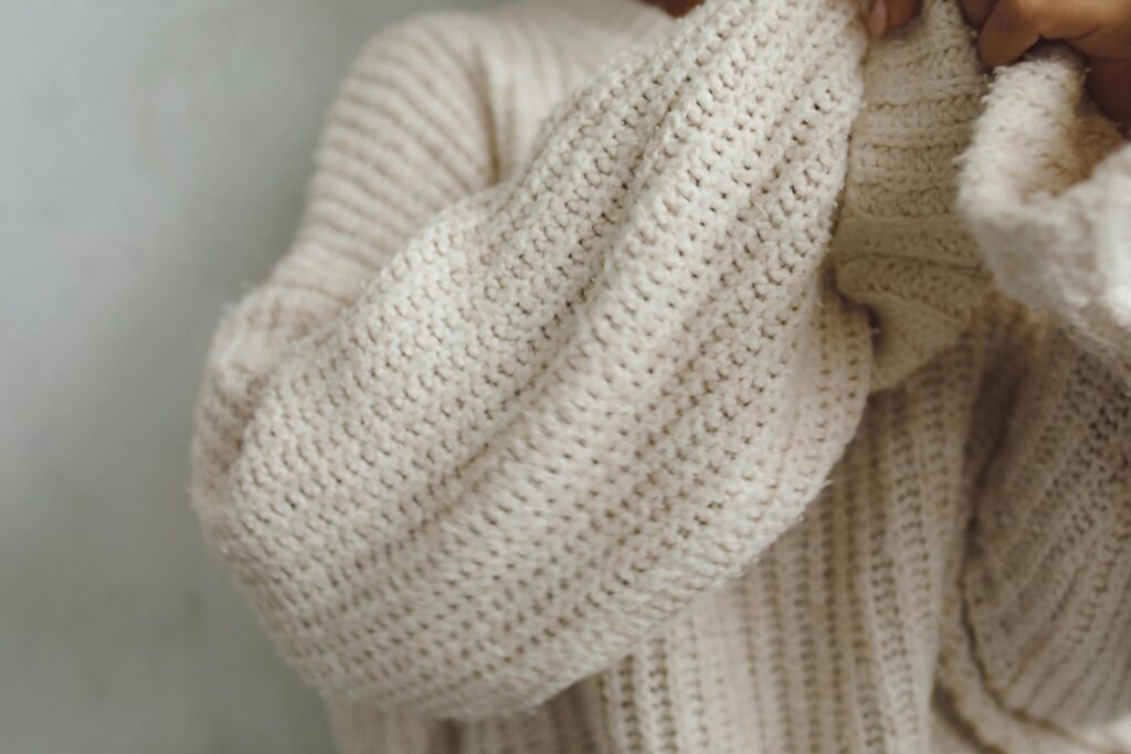Soft beige knitted sweater captured in a cozy close-up view.
